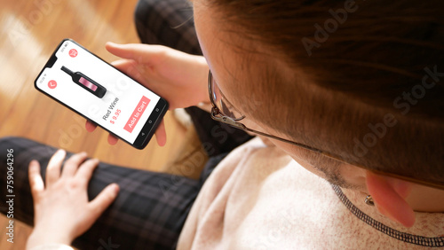 A young man buying a bottle of red wine in an online grocery store