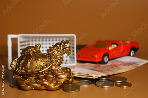A statuette of a metal dragon on the background of a shopping basket and a car.