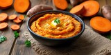 Bowl of Mashed Sweet Potatoes with Butter on a Wooden Table
