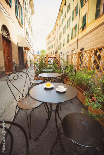 Fototapeta Naklejka Na Ścianę i Meble -  A cup of coffee and juice on table, in italian street, mediterranean style. Street view of a summer terrace cafe with table and chairs. Cup of italian espresso on a table in a street cafe. Urban scene