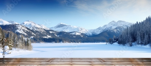 Winter-themed wooden table with space for custom display. Snowy landscape outdoors with mountains and dock in the distance.