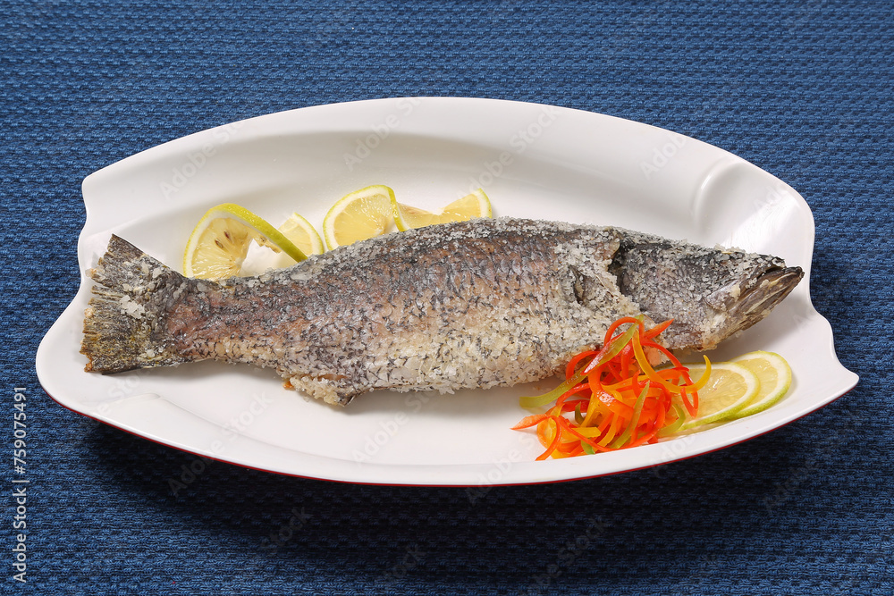 Tasty baked whole fish on baking paper. Baked sea bream with lemon, onion, herbs, cherry tomatoes, spices. Grilled delicious fish. Diet and healthy food