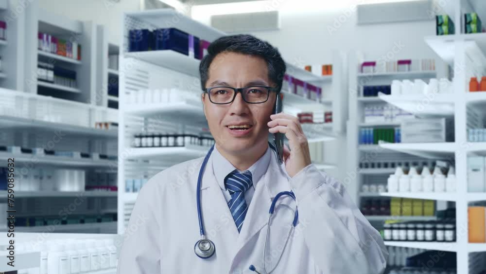 Close Up Of Asian Male Doctor With Stethoscope Talking On Smartphone While Standing In Pharmacy Close Up Of Asian Male Doctor With Stethoscope Talking On Smartphone While Standing In Pharmacy