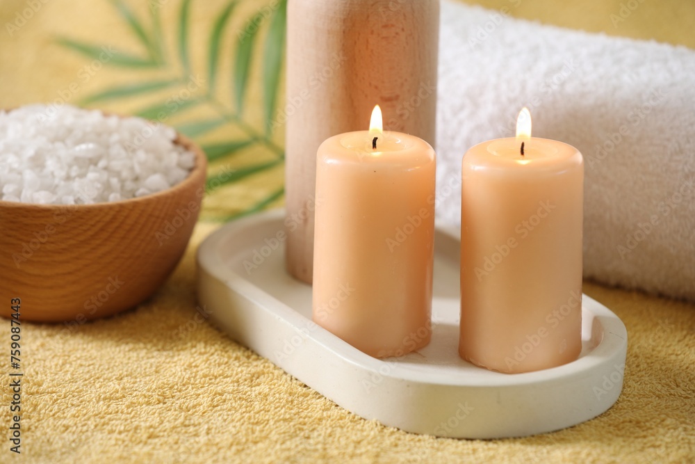 Spa composition. Burning candles, sea salt and towel on soft yellow fabric Spa composition. Burning candles, sea salt and towel on soft yellow fabric