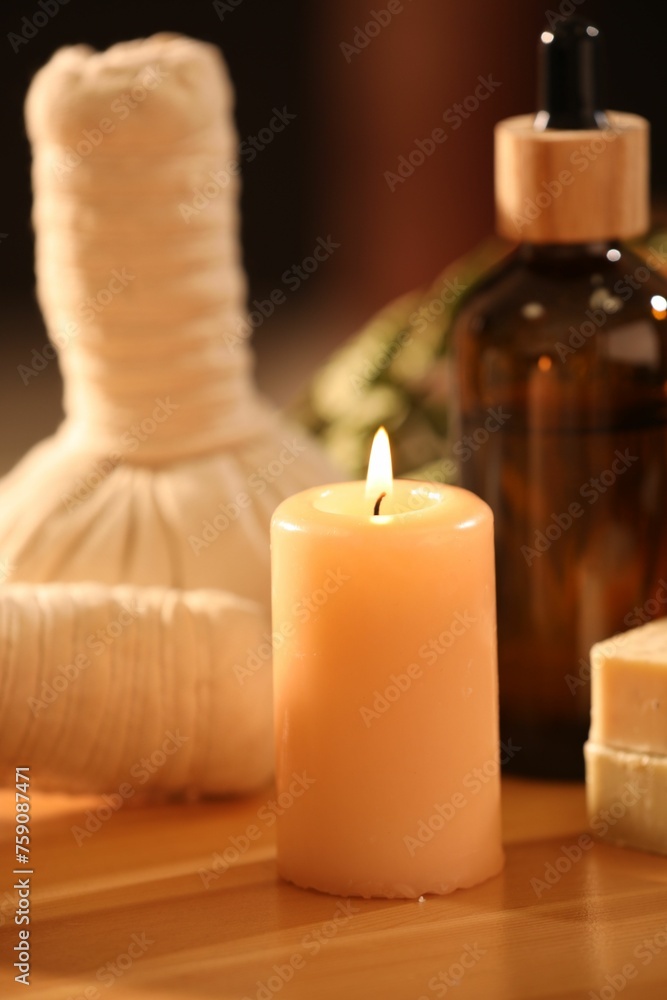 Spa composition. Cosmetic products, herbal bags and burning candle on wooden table, closeup Spa composition. Cosmetic products, herbal bags and burning candle on wooden table, closeup