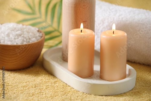 Spa composition. Burning candles  sea salt and towel on soft yellow fabric