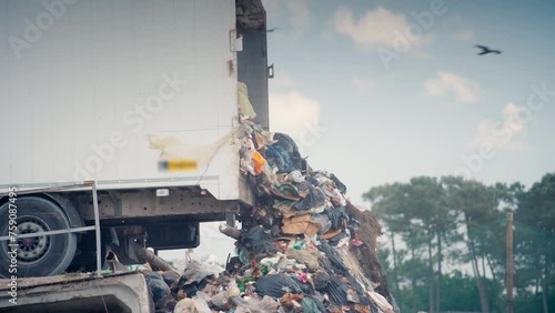 Long shot of a semi-trailer unloads garbage at landfill site.
