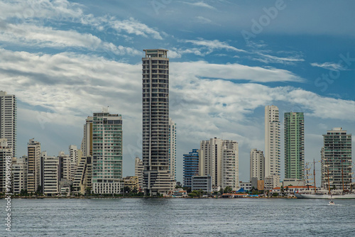 Cartagena, Colombia - July 25, 2023: Tall luxury modern apartment buildings at Bocagrande Neighborhood under blue cloudscape. Tall ship docked at Naval Base  photo