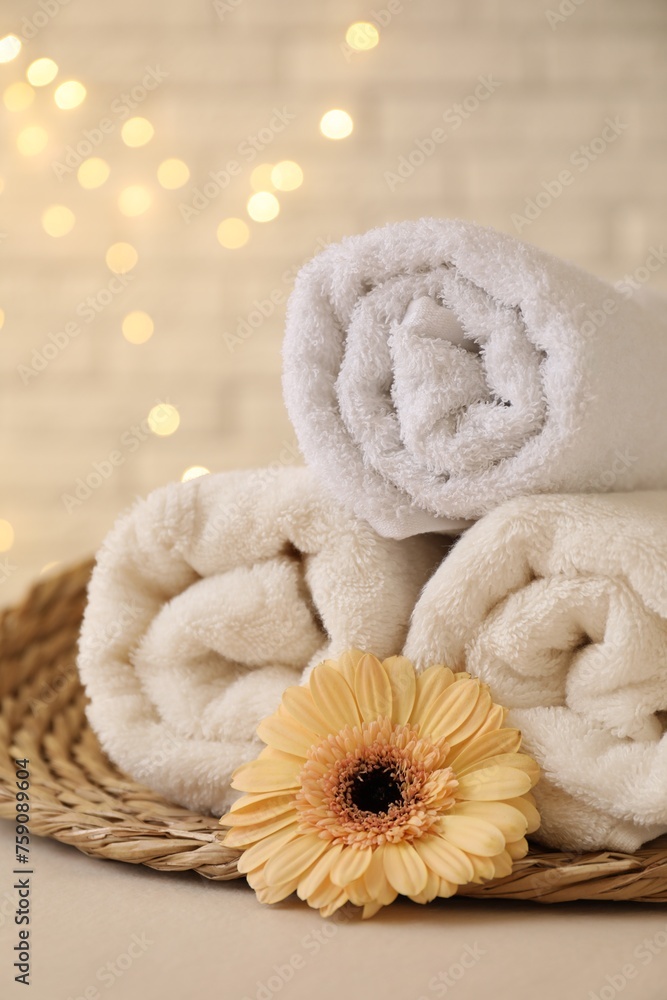 Rolled terry towels and flower on white table near brick wall indoors Rolled terry towels and flower on white table near brick wall indoors