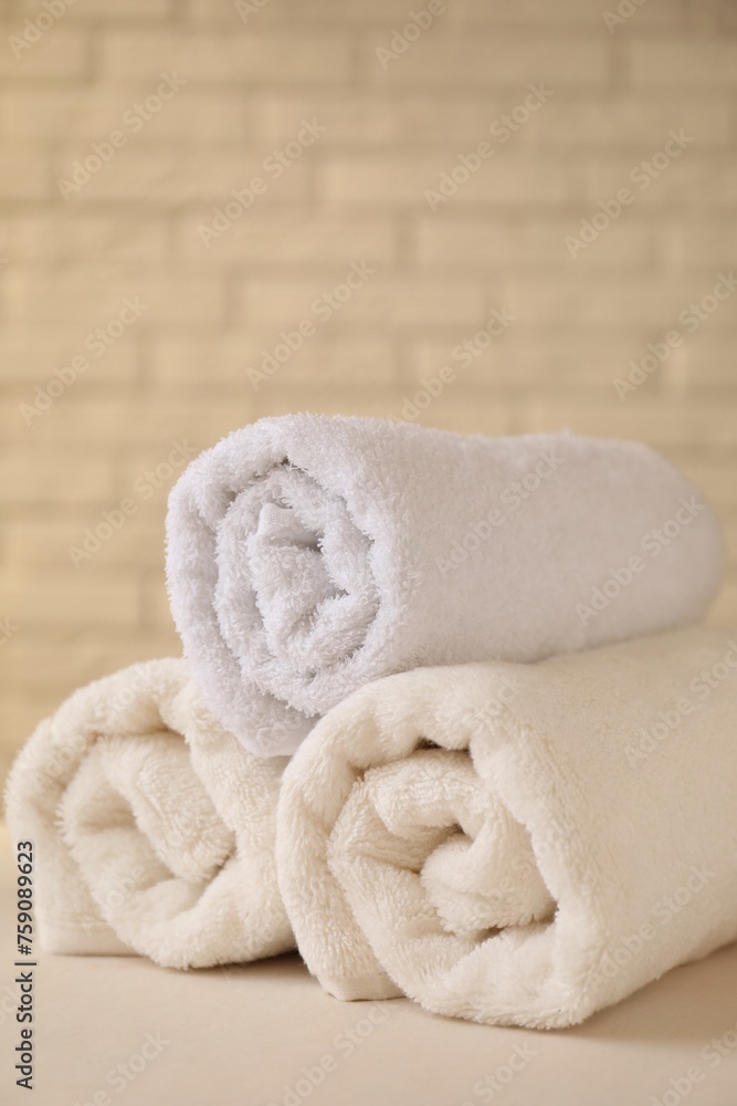Rolled terry towels on white table near brick wall indoors, closeup. Space for text Rolled terry towels on white table near brick wall indoors, closeup. Space for text