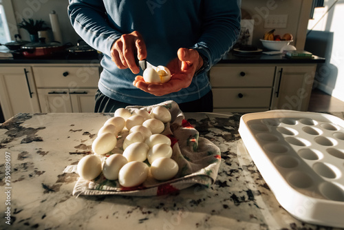 Boiled eggs being cut in half with a knife.  photo
