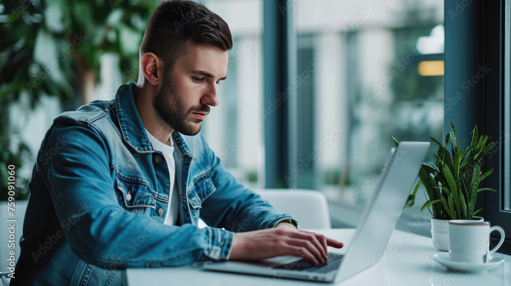 Man smiling while working on a laptop in a modern office environment Man smiling while working on a laptop in a modern office environment