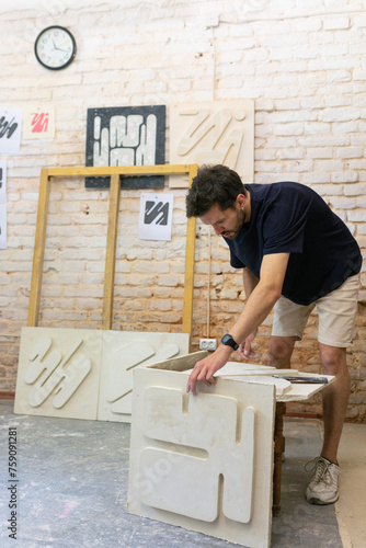 man rearranging clay slabs photo