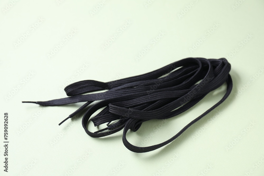 Stylish black shoe laces on light olive background Stylish black shoe laces on light olive background
