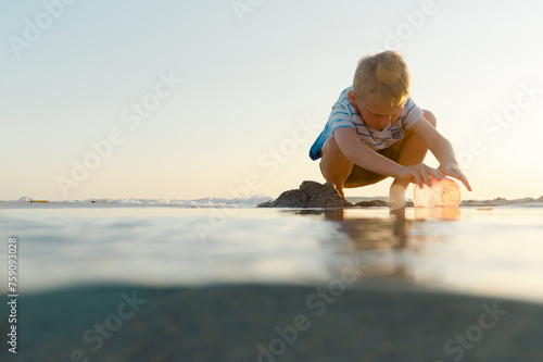 Boy playing in the sand at sunset on the beach photo