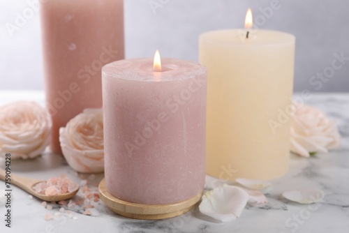 Spa composition with burning candles, flowers and sea salt on white marble table