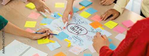 Professional startup group share creative marketing idea by using mind map. Young skilled business people brainstorm business plan while writing sticky notes. Focus on hand. Closeup. Variegated.