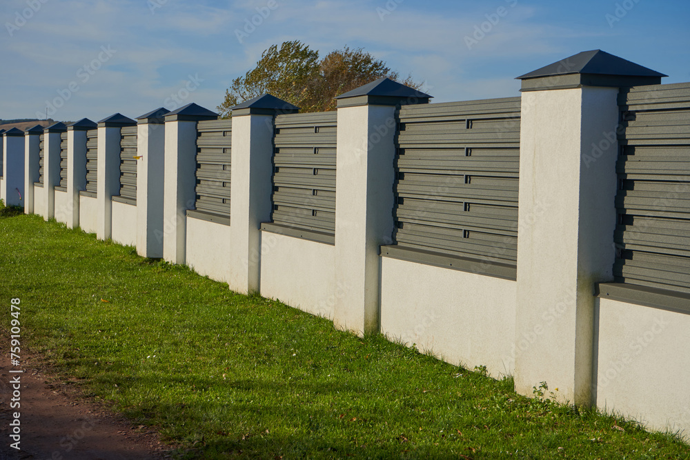 Naklejka premium a fence made of a wall and a metal profile, a new fence made of metal profile with white columns has been built, protection of the territory