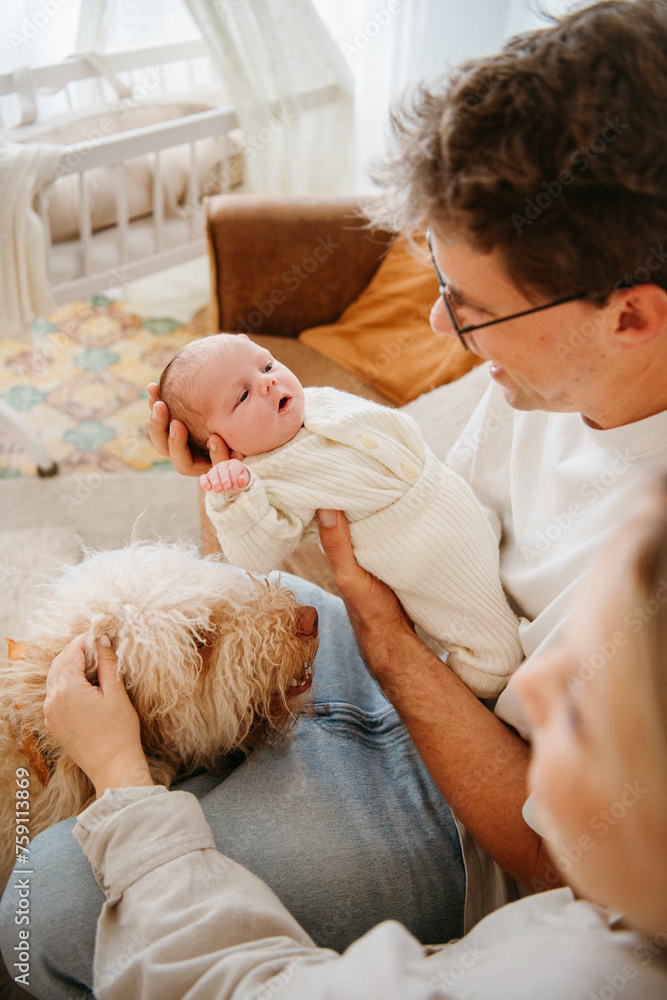 Newborn baby being held by father while introducing her to the dog Newborn baby being held by father while introducing her to the dog