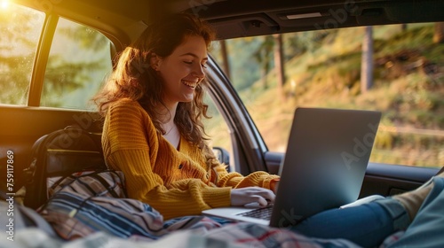 Woman sits comfortably in the open trunk of a car, her laptop resting on her lap as she enjoys the freedom of remote work photo