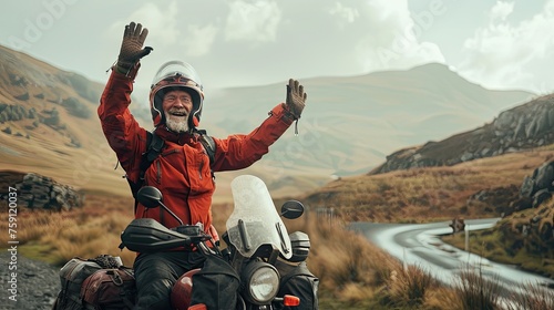 A best ager motor biker stands amidst lush nature  flashing a victory sign with hand  symbolizing triumph in conquering the scenic terrain