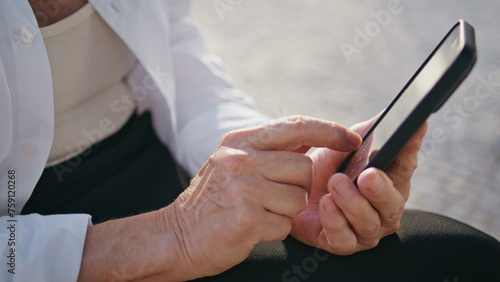 Senior hands touching cellphone screen browsing internet on street close up. © stockbusters