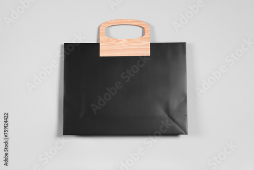 One black paper shopping bag on grey background, top view