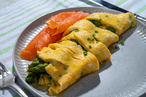 Chicken eggs omelette stuffed with green asparagus, served with smoked scottisch salmon fish, french cuisine photo