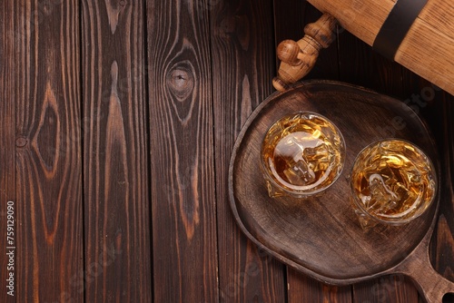 Whiskey with ice cubes in glasses and barrel on wooden table, top view. Space for text