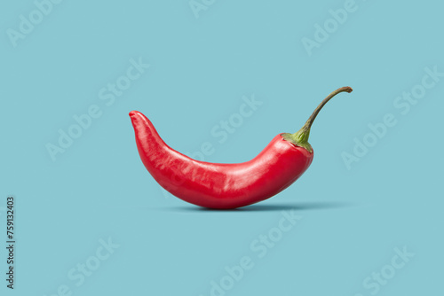 Red chili pepper with green stalk over blue studio background