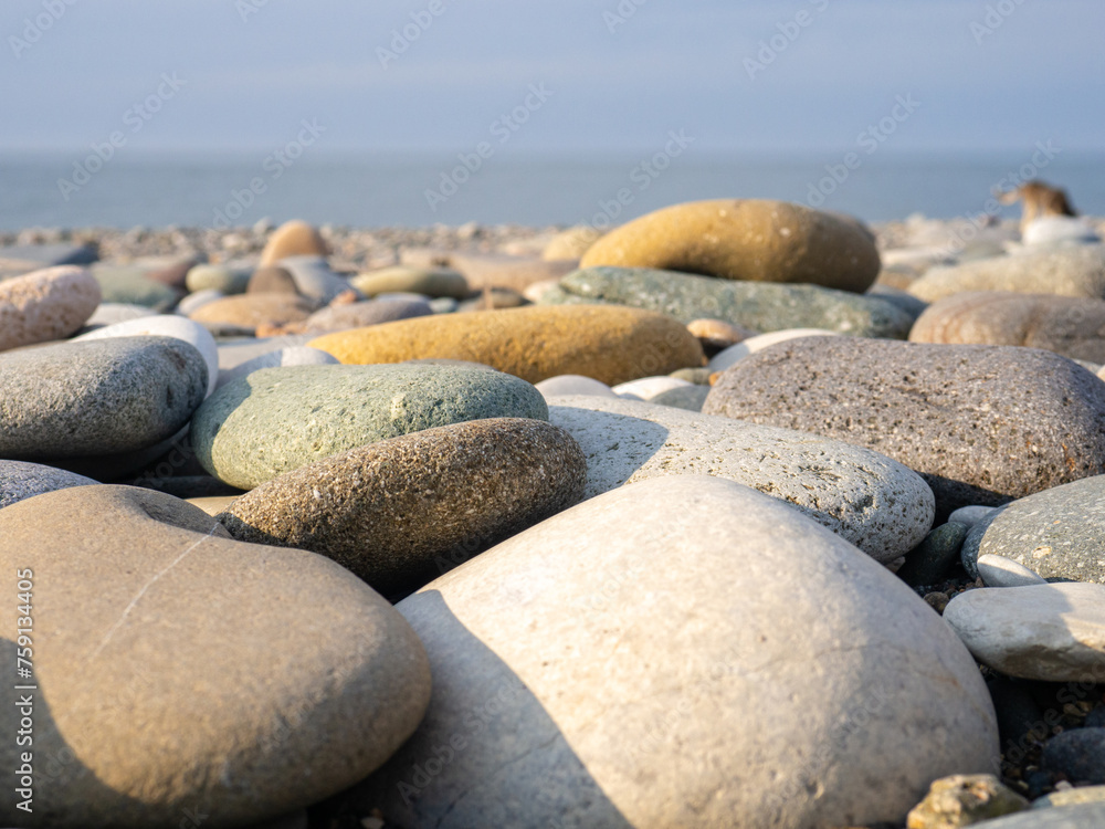 Gray sand and stones close-up on the beach. Stone in the foreground. Beach in winter. Sea coast soil. Gray sand and stones close-up on the beach. Stone in the foreground. Beach in winter. Sea coast soil.