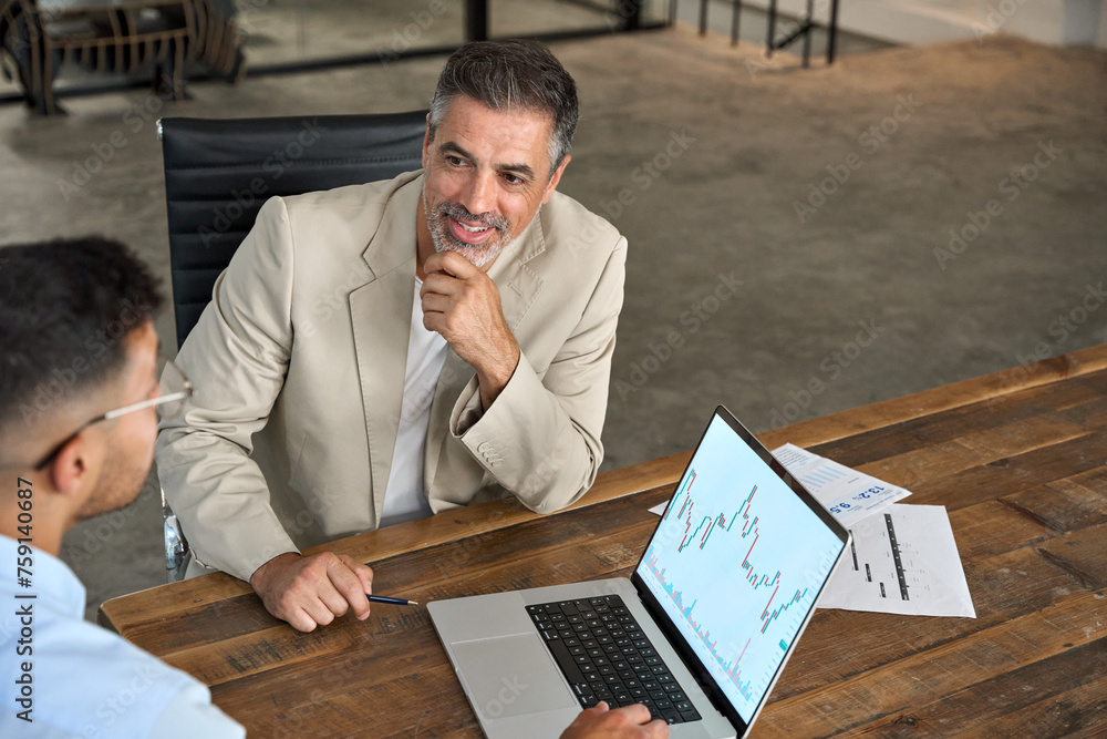 © insta_photos - Professional advisor consulting business man investor explaining financial trade stock market trends in crypto exchange investing planning using laptop computer at office meeting. Copy space.