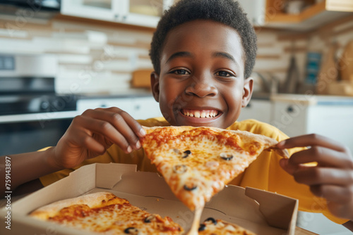 Boy of African American ethnicity eats pizza indoors