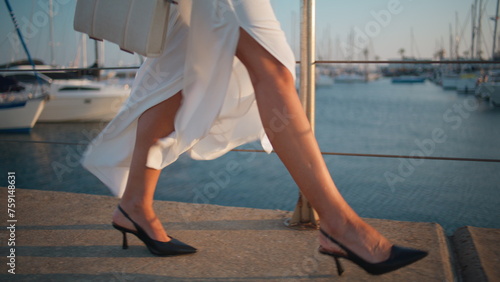 Fotografie Girl feet strolling quay in trendy high-heels close up
