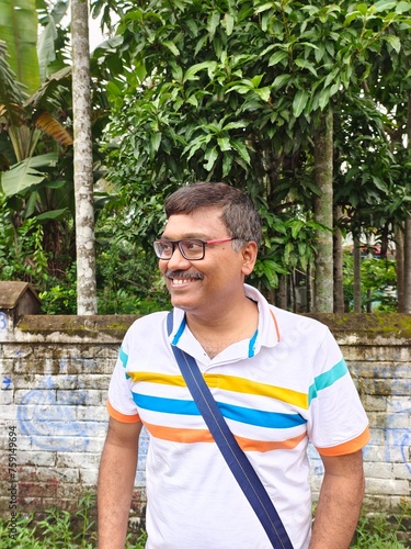 Middle aged Indian man wearing white T shirt and looking happy photo