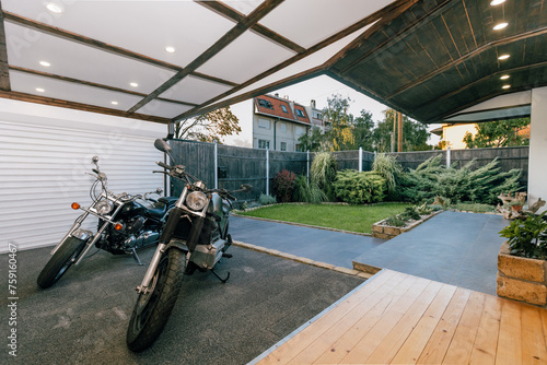 Motorbikes parked in an open garage in a landscaped house backyard photo