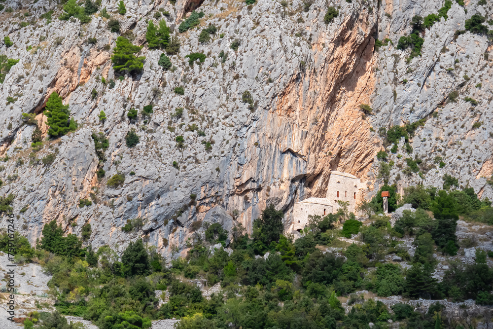 Scenic view of ancient fortress build into massive rock formation in village Kotisina near Makarska, Split-Dalmatia, Croatia, Europe. Hiking in Biokovo nature park in mountain of Dinaric Alps, Balkan