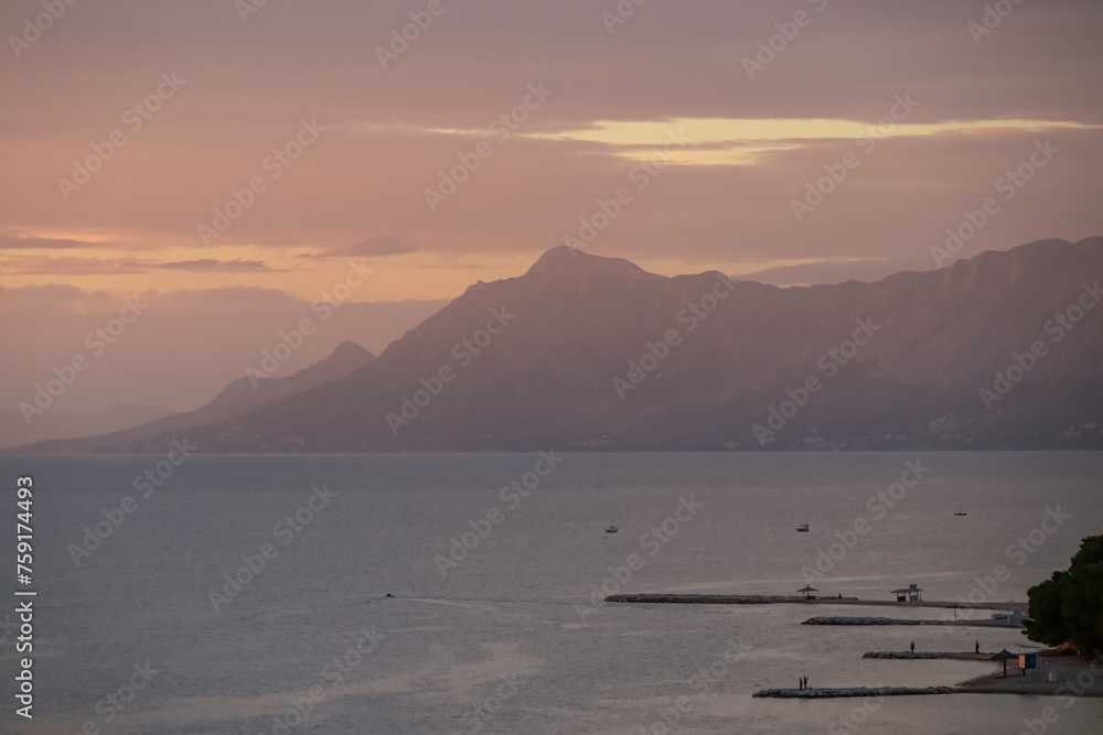 Sunset view of Dalmatian archipelago seen from coastal town Makarska, Split-Dalmatia, Croatia, Europe. Coastline of Makarska Riviera, Adriatic Sea. Balkans in summer. Scenic port. Tranquil atmosphere
