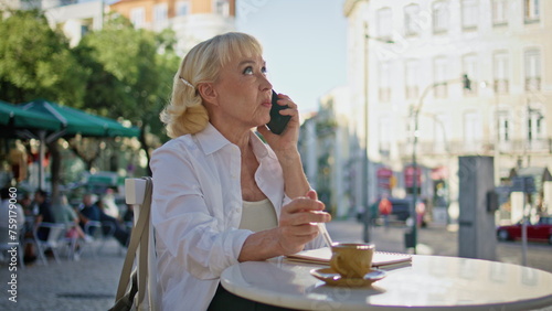 Aged businesswoman dissatisfied smartphone communication at open cafe close up.