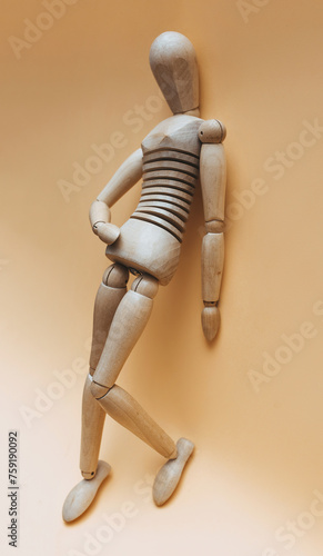 A wooden mannequin (female or male) stands with one leg raised in a waiting position. The concept of prostitution, gigolo, selling love and sexual paid services.