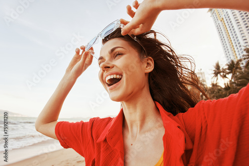 Smiling woman in trendy sunglasses enjoying the freedom of a colorful seaside lifestyle
