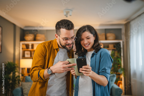Adult couple man and woman husband wife have a cup of coffee use mobile phone search internet social network happy smile