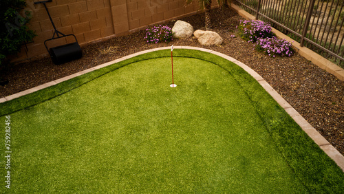 An artificial grass putting green in a desert landscaped backyard.