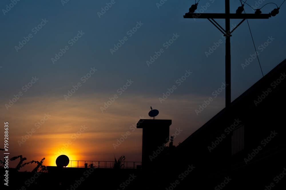 Silhouette of a tower with a sun setting behind it.