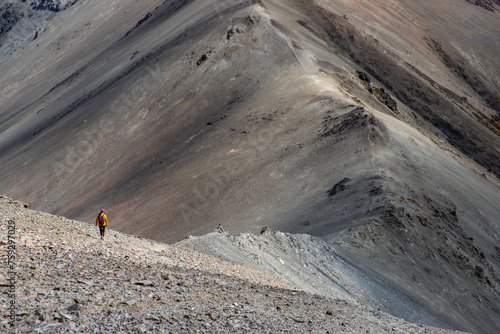 hiker girl walking down a very steep rocky hill from the summit of castle hill peak, torlesse tussocklands national park, new zealand south island photo