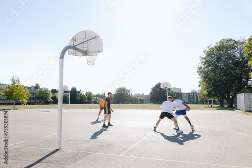 A group of friends playing basketball together outside. photo