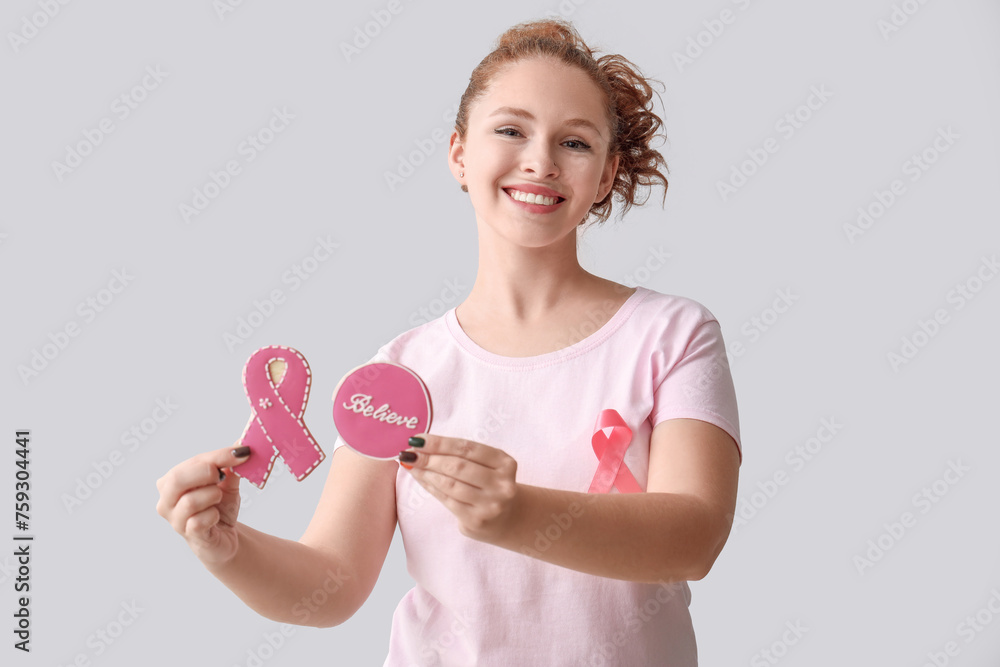Young woman with ribbon and cookies on light background. Breast cancer awareness concept Young woman with ribbon and cookies on light background. Breast cancer awareness concept
