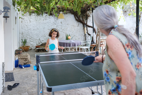 Kid playing ping pong outdoor with grandmother photo