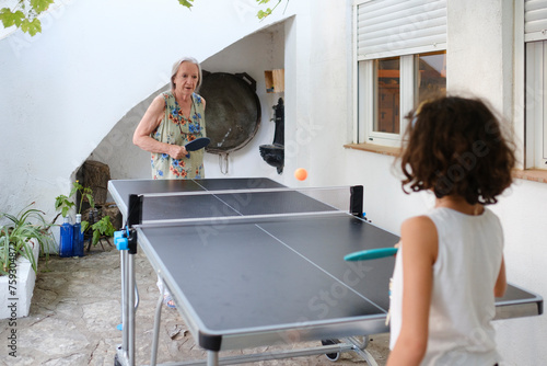 Senior woman playing ping pong outdoor with granddaughter