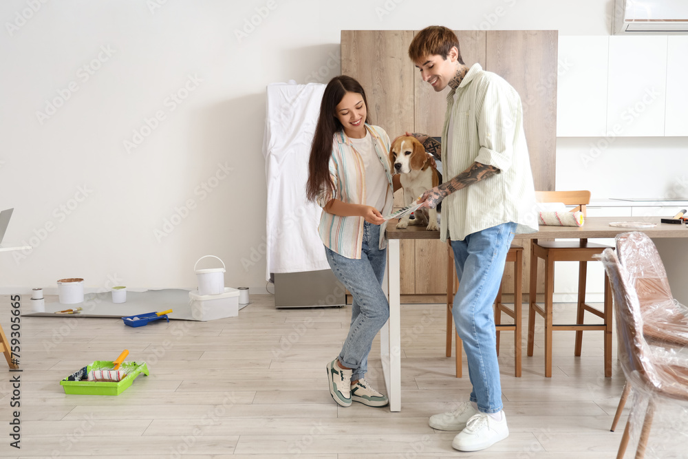 Young couple with paint color palettes and Beagle dog during repair in their new house Young couple with paint color palettes and Beagle dog during repair in their new house